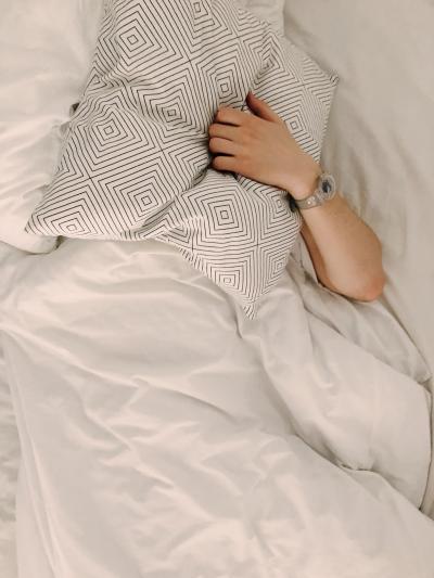 Person ligger i säng med kudde över ansiktet